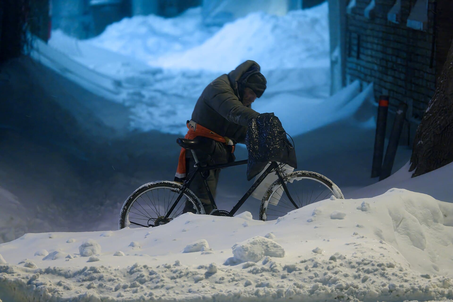 A man pushing his bicycle through waist-deep snowdrifts on a Quebec City street during the February 2025 blizzard